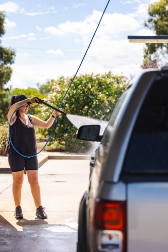 Woman washing vehicle in self-service car wash bay - Australian Stock Image