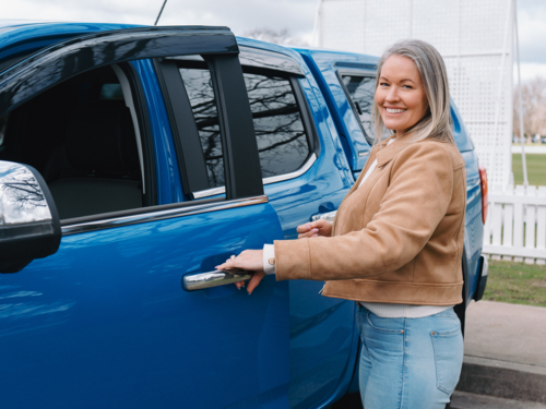 Woman wearing brown jacket opens passenger car door - Australian Stock Image