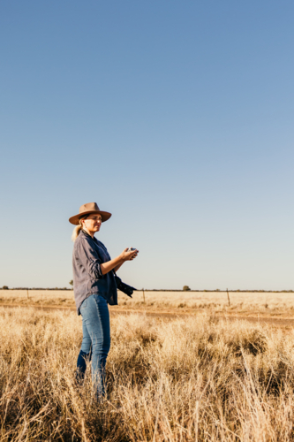 Woman wearing hat standing in a dry grassy field - Australian Stock Image