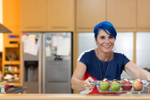 Woman with blue hair preparing apples for baking - Australian Stock Image