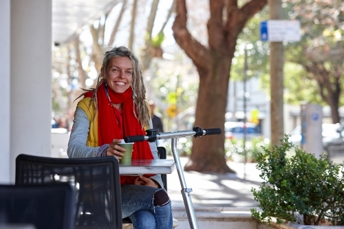 Woman with dreadlocks and scooter at a cafe in the city - Australian Stock Image