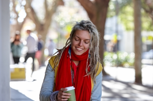 Woman with dreadlocks drinking coffee outdoors at cafe