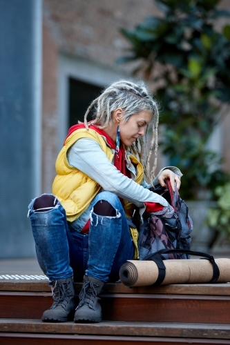 Woman with dreadlocks getting item from backpack - Australian Stock Image