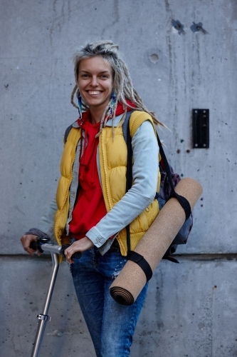 Woman with dreadlocks on electric scooter going to a yoga class - Australian Stock Image