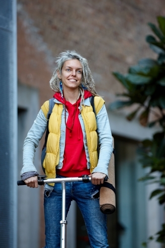 Woman with dreadlocks on electric scooter going to her yoga class - Australian Stock Image