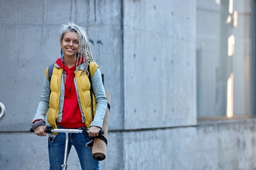 Woman with dreadlocks riding electric scooter - Australian Stock Image