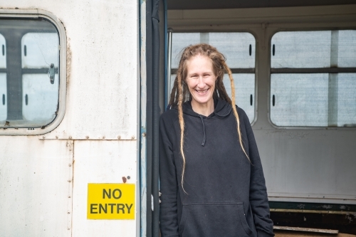 Woman with dreadlocks standing in the doorway of an old bus. - Australian Stock Image