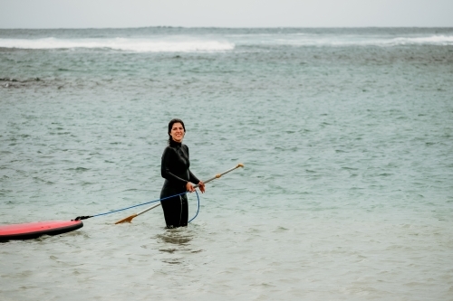 Woman with stand up paddle board in the ocean. - Australian Stock Image