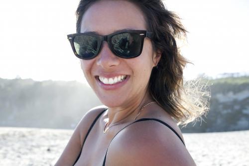 Woman with sunglasses on smiling at the beach
