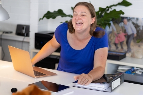 woman working from home with laptop and file on desk
