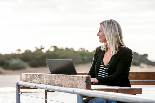 Woman working on her laptop in coastal location