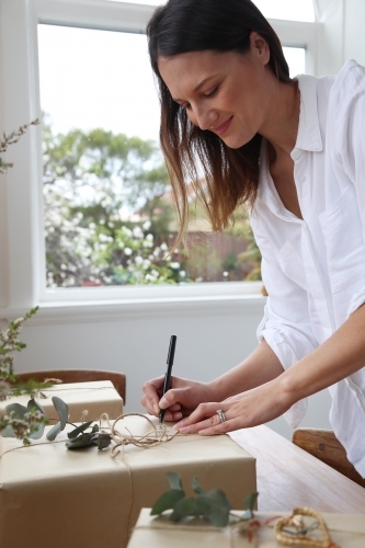 Woman writing gift tag for present