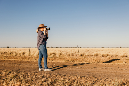 Women photographer standing in paddock taking photo - Australian Stock Image
