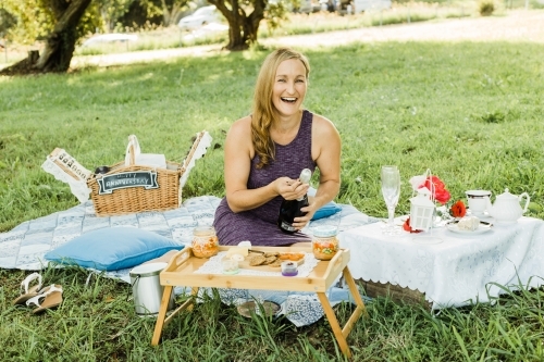 Women sitting at on picnic rug with champagne