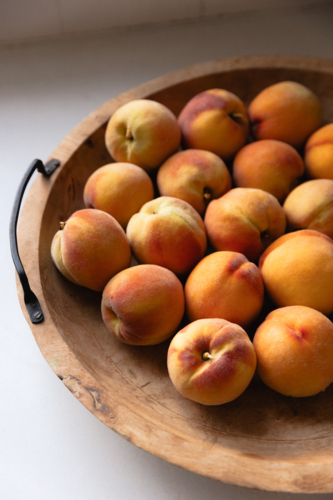 Wooden bowl in natural light full of ripe home grown peaches - Australian Stock Image