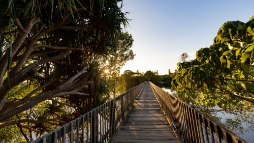 Wooden footbridge leading across Simpsons Creek at Brunswick Heads - Australian Stock Image