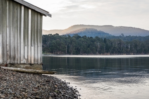 Wooden shack beside water - Australian Stock Image