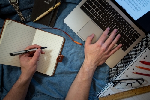 Work, Study, or School from Home, hands and book and laptop - Australian Stock Image
