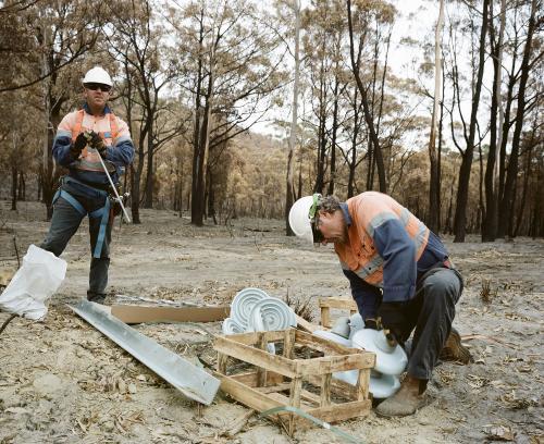 Workmen repairing power lines in bushfire ravaged landscape