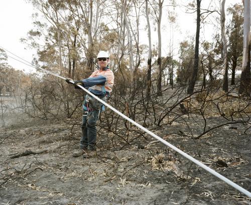 Workmen repairing power lines in bushfire ravaged landscape - Australian Stock Image