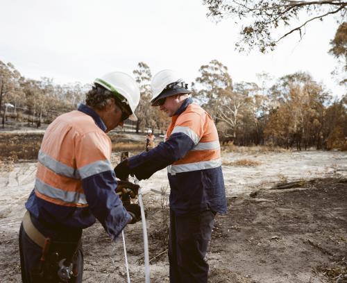 Workmen repairing power lines in bushfire ravaged landscape