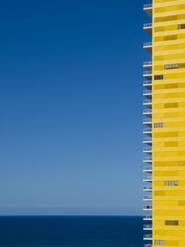 Yellow apartment building with blue sky and sea - Australian Stock Image