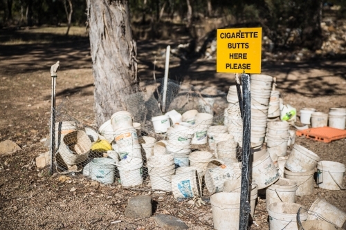 Yellow smoking sign on fence with buckets - Australian Stock Image