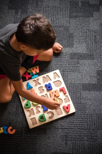 Young Aboriginal boy doing a letter puzzle - Australian Stock Image