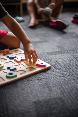 Young Aboriginal boy playing with alphabet letter puzzle pieces - Australian Stock Image