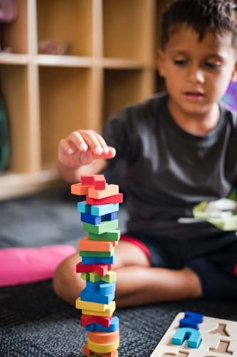 Young Aboriginal boy playing with alphabet letter puzzle pieces - Australian Stock Image