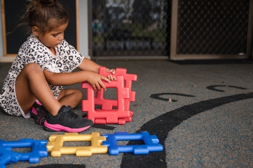 Young Aboriginal girl playing at preschool with plastic toy - Australian Stock Image