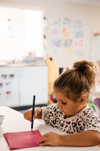 Young Aboriginal girl writing at preschool - Australian Stock Image