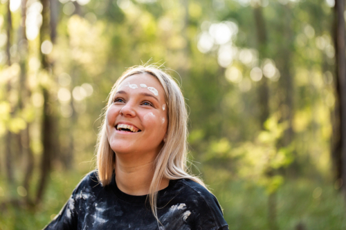 Young aboriginal woman in her twenties laughing in green bushland - Australian Stock Image