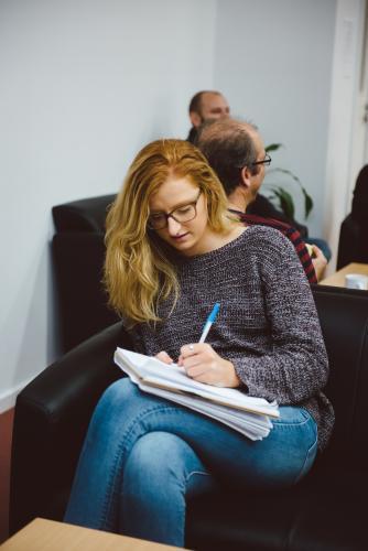 Young adult with glasses writing notes at university - Australian Stock Image