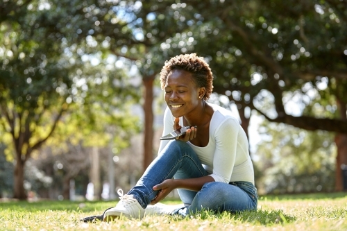 Young African woman enjoying time in sunshine with mobile phone