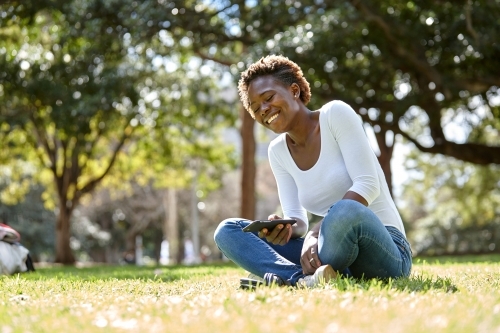Young African woman laughing in sunshine at park - Australian Stock Image