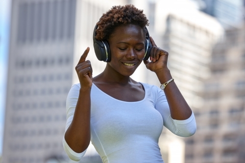 Young African woman listening to music smiling - Australian Stock Image