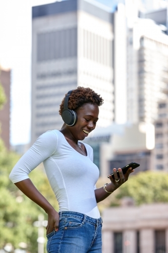 Young African woman listening to songs on mobile phone - Australian Stock Image