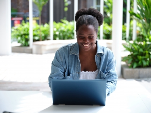 Young African woman using a computer on university campus - Australian Stock Image