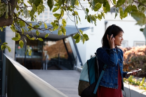 Young Asian female checking mobile phone under tree