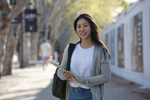 Young Asian female university student carrying study notes - Australian Stock Image