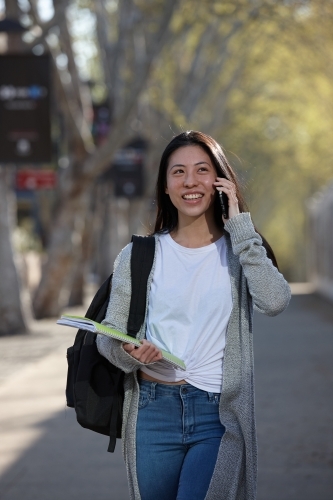 Young Asian female university student on mobile phone - Australian Stock Image