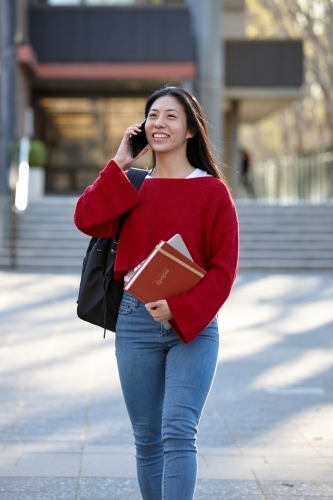 Young Asian female university student on mobile phone - Australian Stock Image