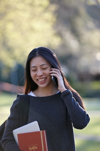 Young Asian female university student on mobile phone - Australian Stock Image