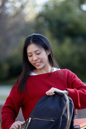 Young Asian female university student opening bag - Australian Stock Image