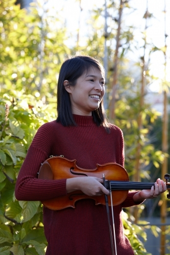 Young Asian female violin player practising outdoors - Australian Stock Image