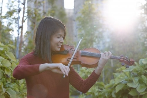 Young Asian female violin player practising outdoors