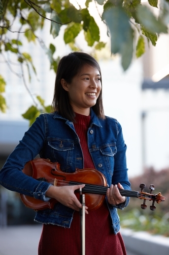 Young Asian female violin player practising outdoors - Australian Stock Image