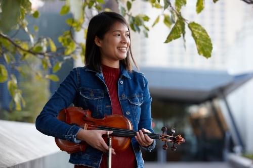 Young Asian female violin player practising outdoors - Australian Stock Image