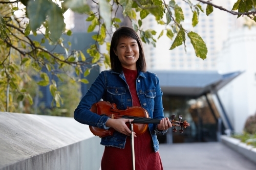 Young Asian female violin player practising outdoors - Australian Stock Image